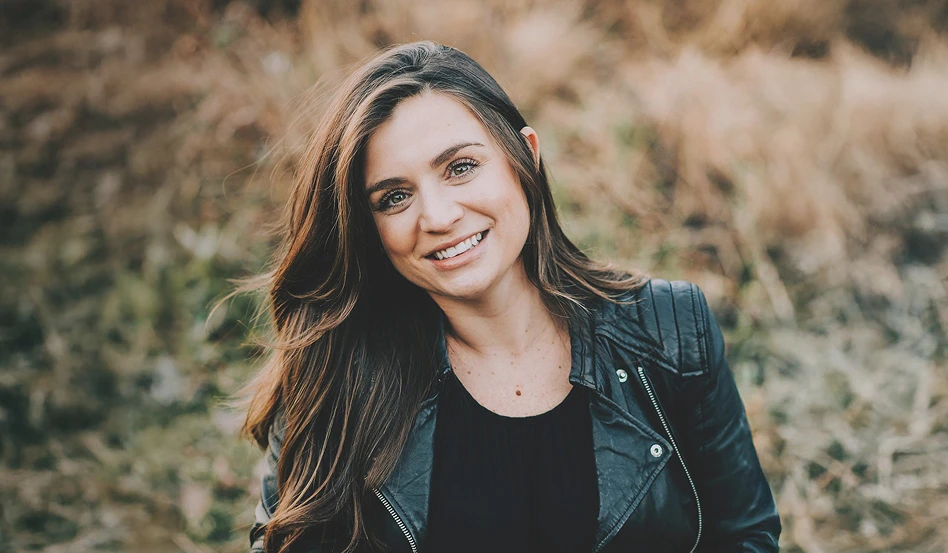 A real patient smiling outside in a field, sharing their story managing vitiligo with Opzelura.