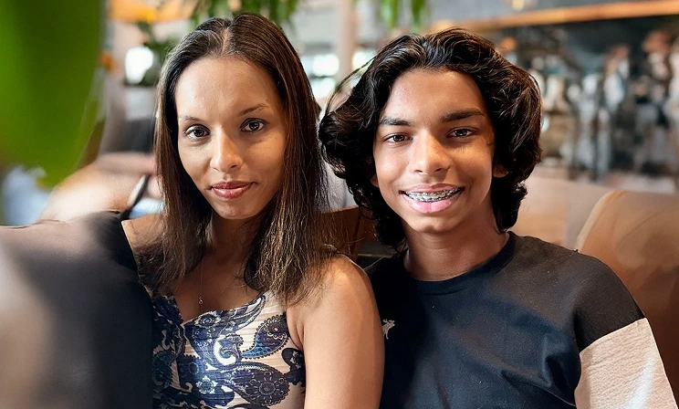 A real patient and caregiver smiling, arm in arm, sharing their story of managing vitiligo with Opzelura.