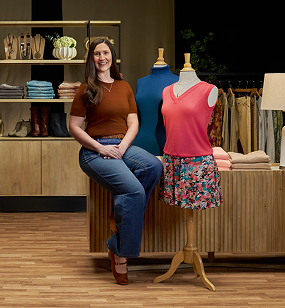 Sarah sitting and smiling in a department store setting, discussing her vitiligo repigmentation with Opzelura. 
