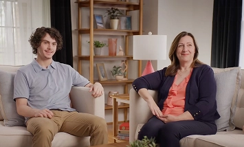 A real patient and caregiver sitting in a living room, sharing their story of managing eczema with Opzelura.