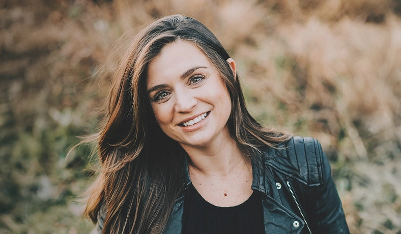 A real patient smiling outside in a field, sharing their story managing vitiligo with Opzelura.