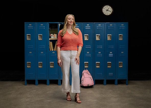 Sam standing in front of lockers, discussing her journey managing vitiligo with Opzelura.