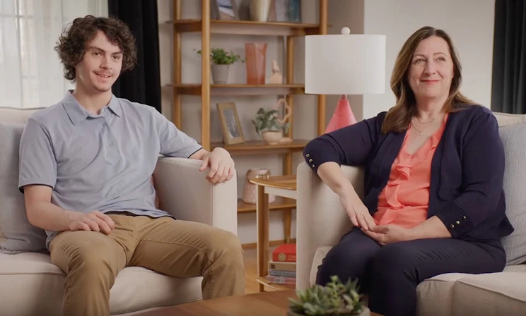 A real patient and caregiver sitting in a living room, sharing their story of managing eczema with Opzelura.