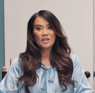 Dr. Lee sitting in a wardrobe and makeup room, discussing how she manages eczema with Opzelura.