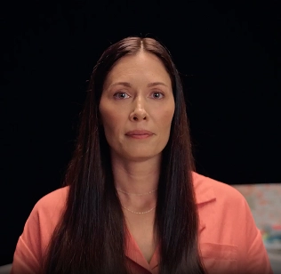 Emily in front of a black background, discussing how she managed eczema with Opzelura.